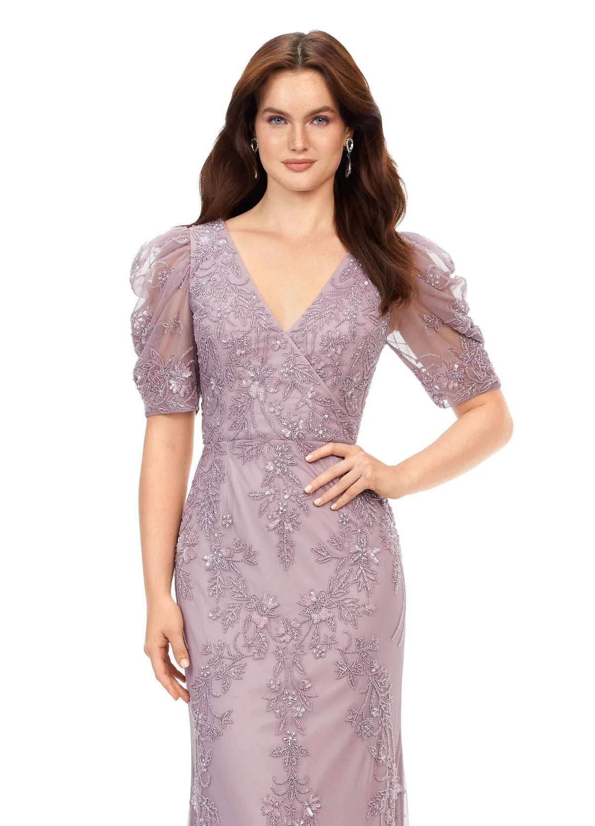 Close up of an elegant evening gown features a delicate floral lace design with subtle embroidery, puff sleeves, and a flattering V-neckline. The form-fitting silhouette flows into a soft train, exuding timeless sophistication.