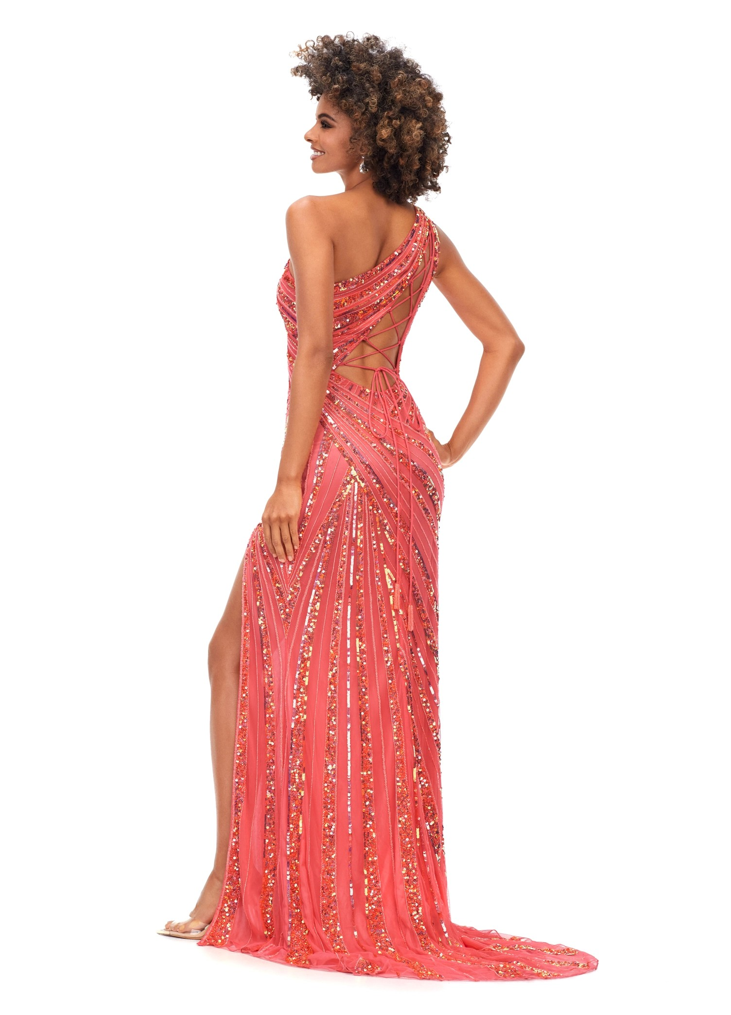 Back View - Stunning coral one-shoulder gown embellished with intricate sequins, offering a high slit for a glamorous finish.