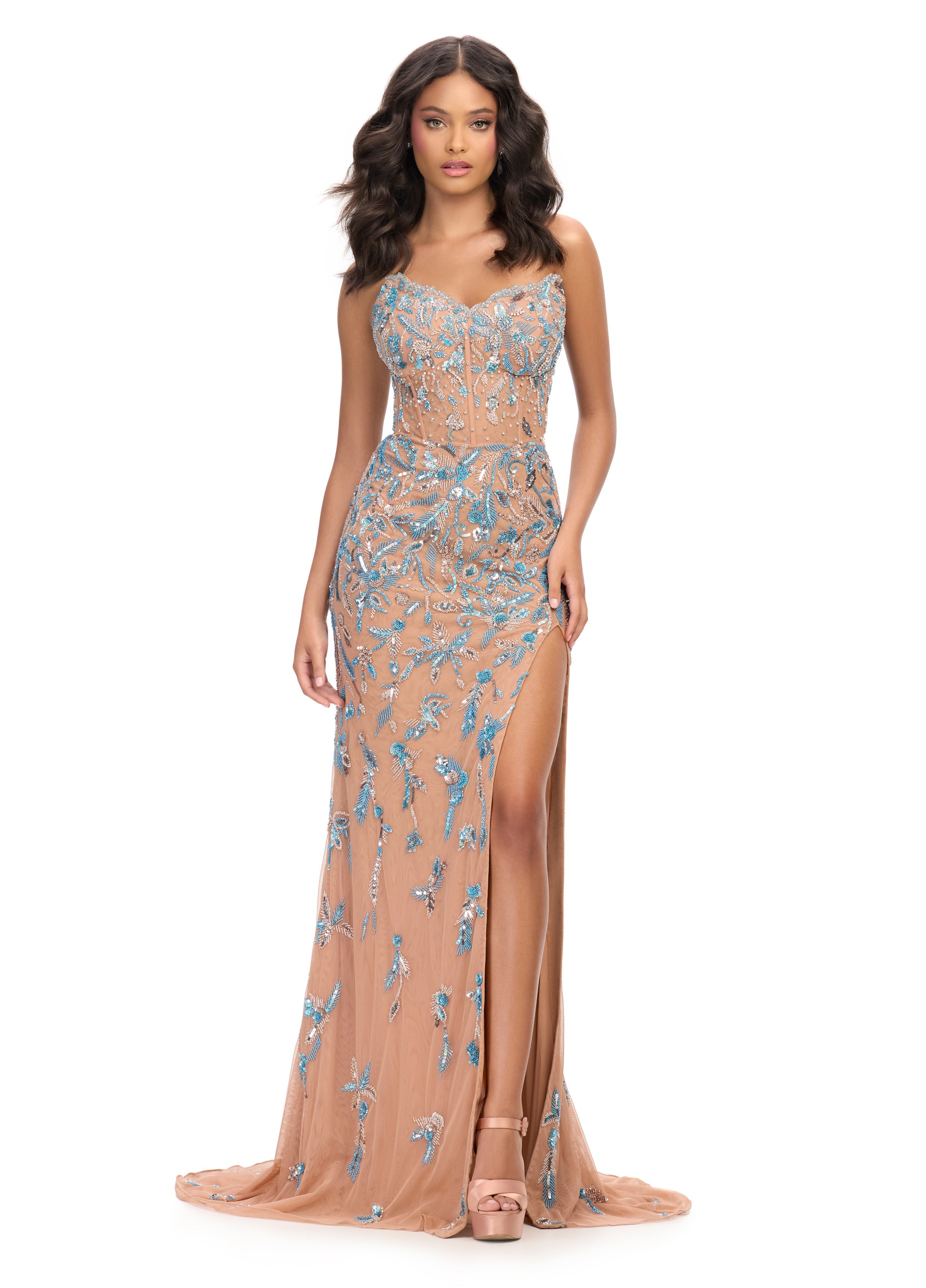 
A sophisticated nude gown embellished with intricate blue beading and embroidery, featuring a strapless bodice, a high side slit, and a sheer overlay that exudes elegance and glamour.