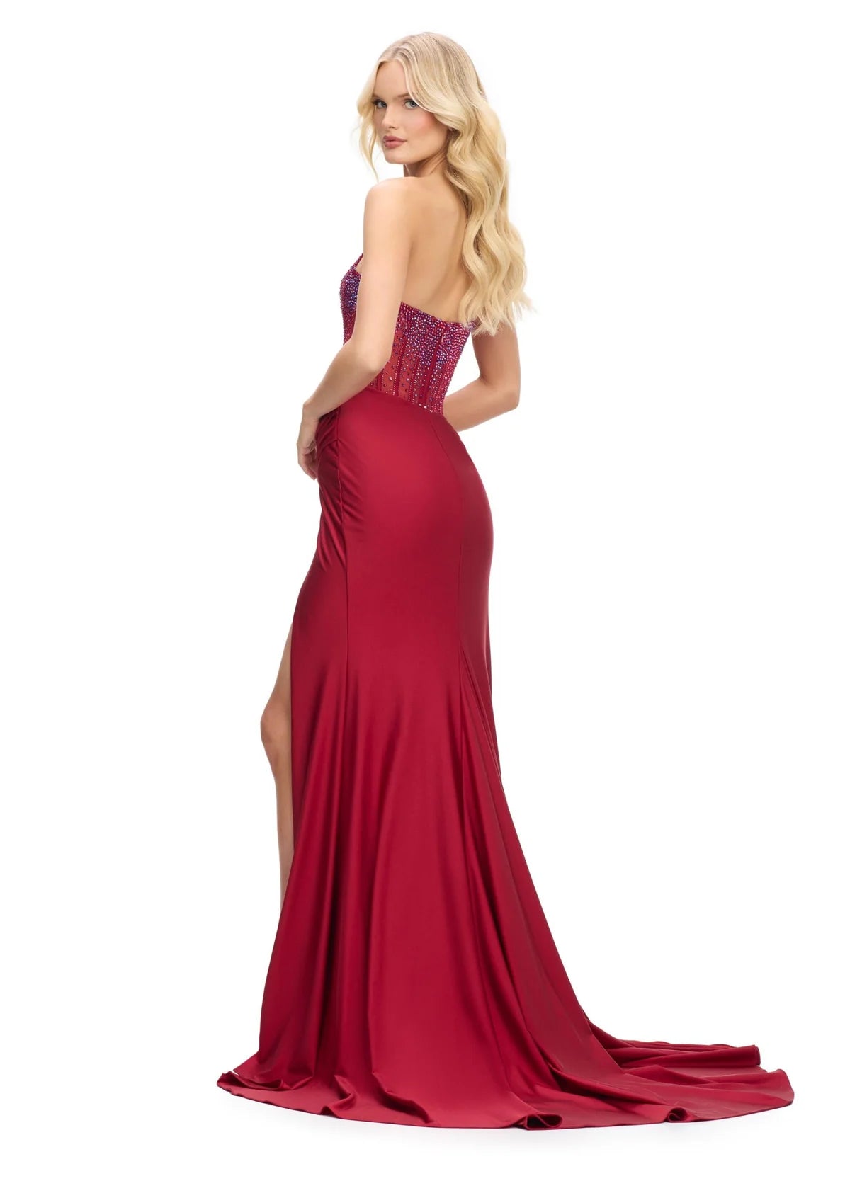 Back view - Red strapless evening gown with an intricately beaded bodice and sheer detailing, complemented by a flowing skirt with a high slit for a glamorous and sophisticated look.