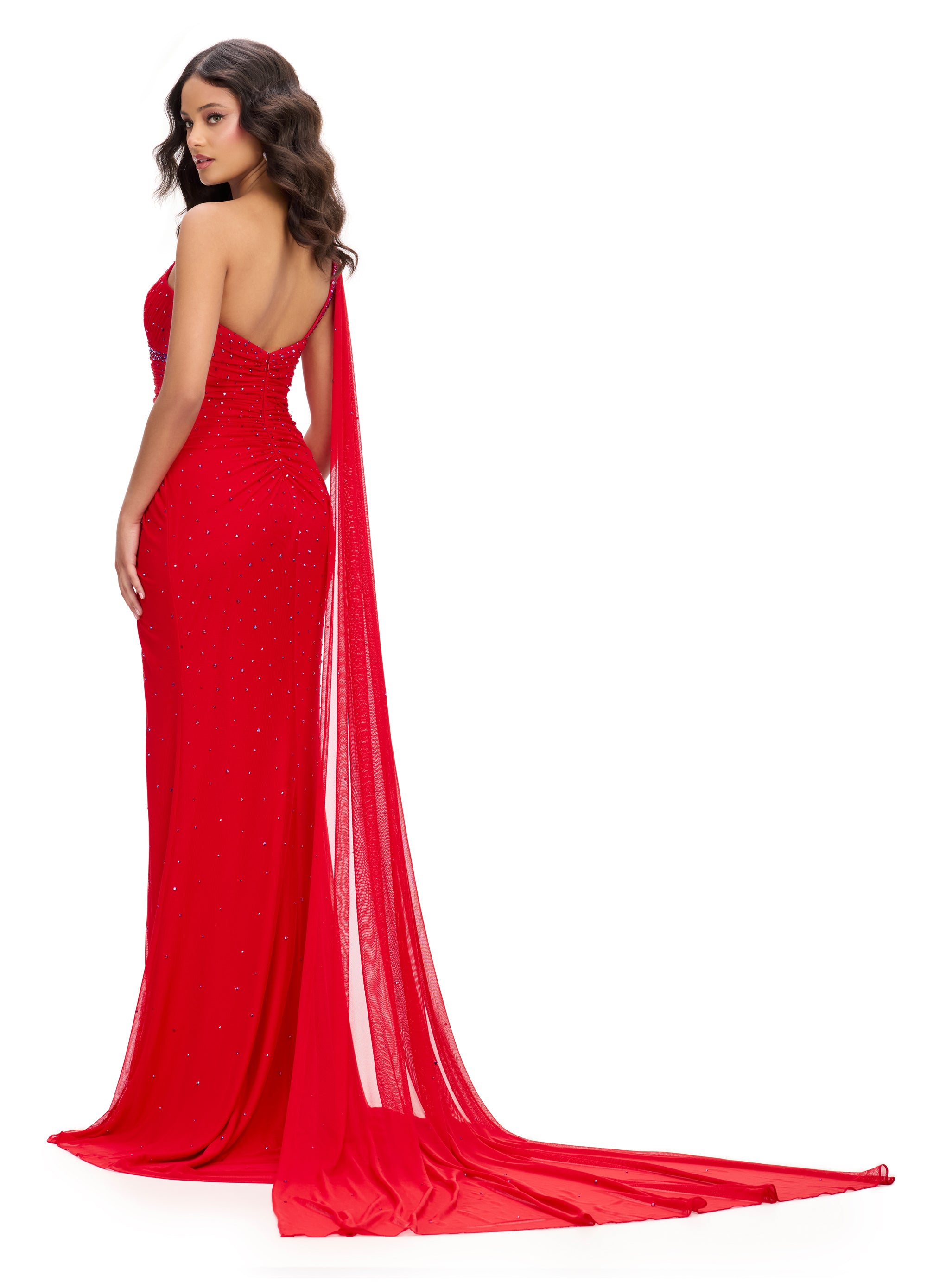 Back view - Red asymmetric one-shoulder evening gown adorned with scattered embellishments, featuring a draped bodice, thigh-high slit, and a flowing sheer cape for a dramatic and elegant silhouette.
