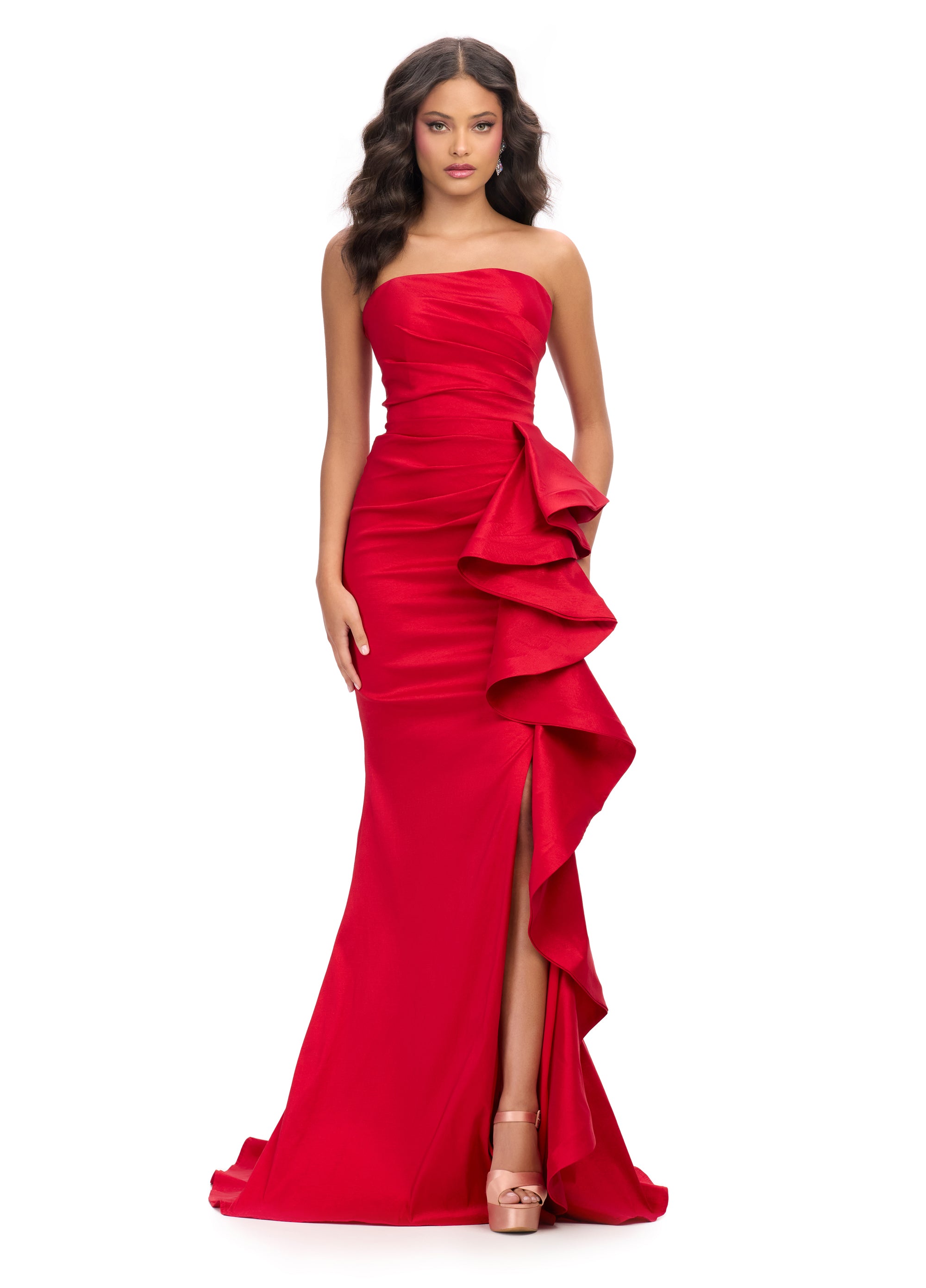 Red strapless evening gown featuring a structured bodice, asymmetrical ruffle detailing cascading along the skirt, and a thigh-high slit for a modern and sophisticated silhouette.