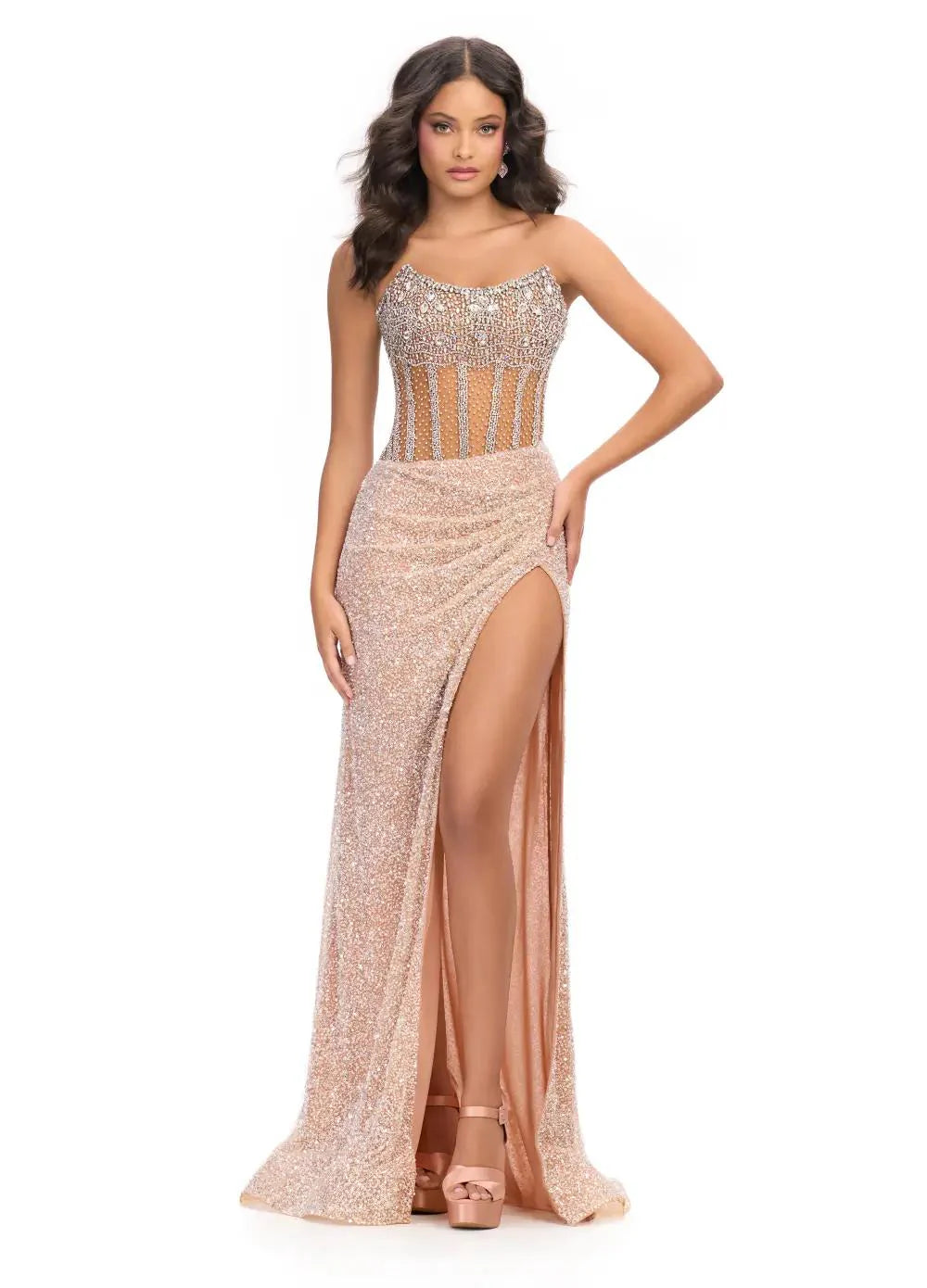 Nude gown with a sheer embellished bodice, fitted sparkling skirt, high slit, and floor-length design.