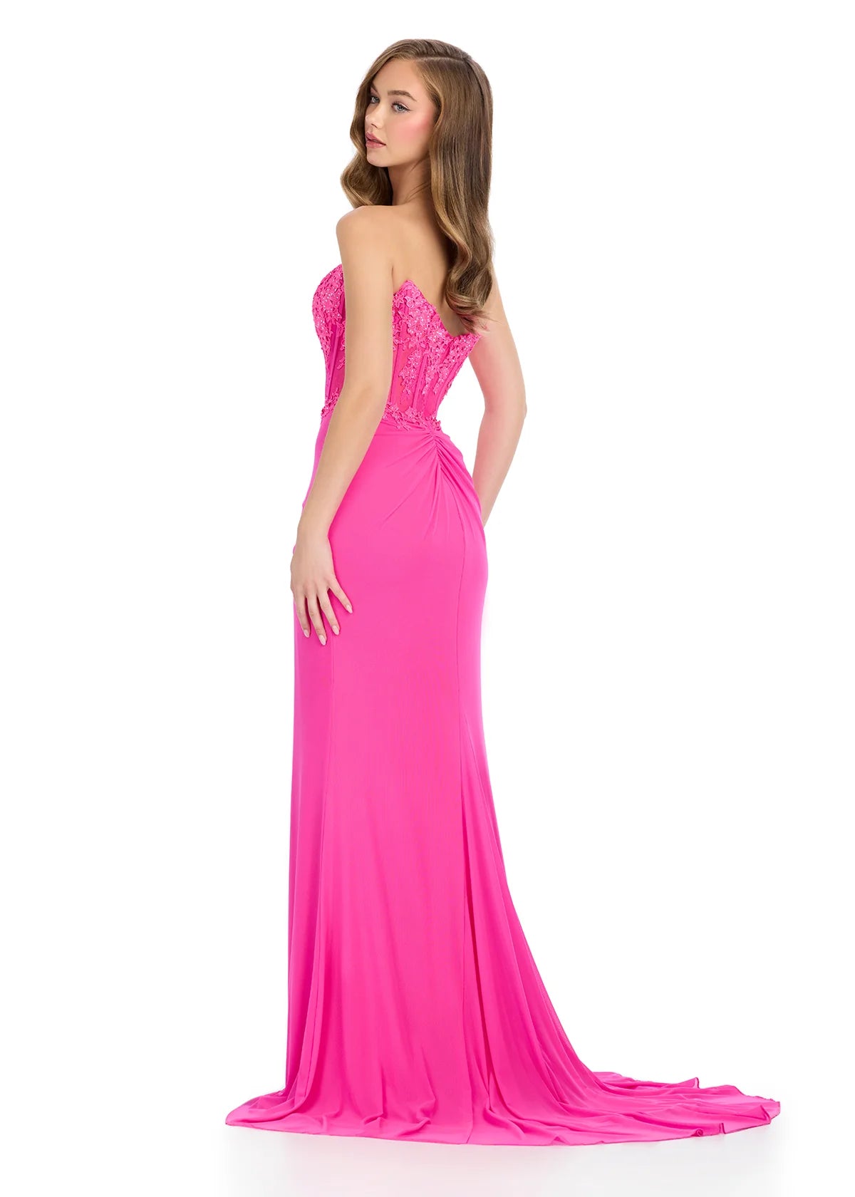 Back view - Elegant hot pink floor-length gown featuring a strapless sweetheart neckline, sheer lace bodice, ruched detailing, cascading ruffle accents, a thigh-high slit, and a flowing train for a dramatic and sophisticated look.
