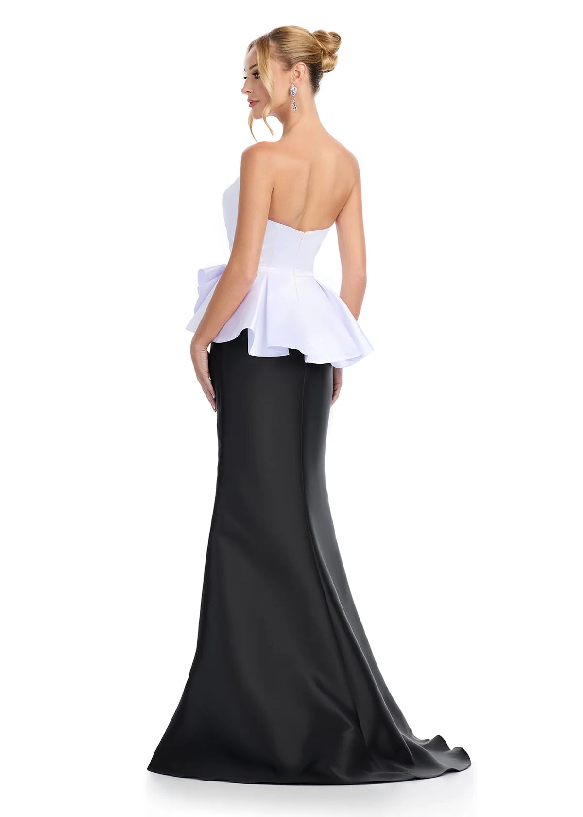 White and black evening gown featuring a strapless white peplum top with sculpted ruffle detailing and a sleek black mermaid skirt for a modern and elegant look. Back view.