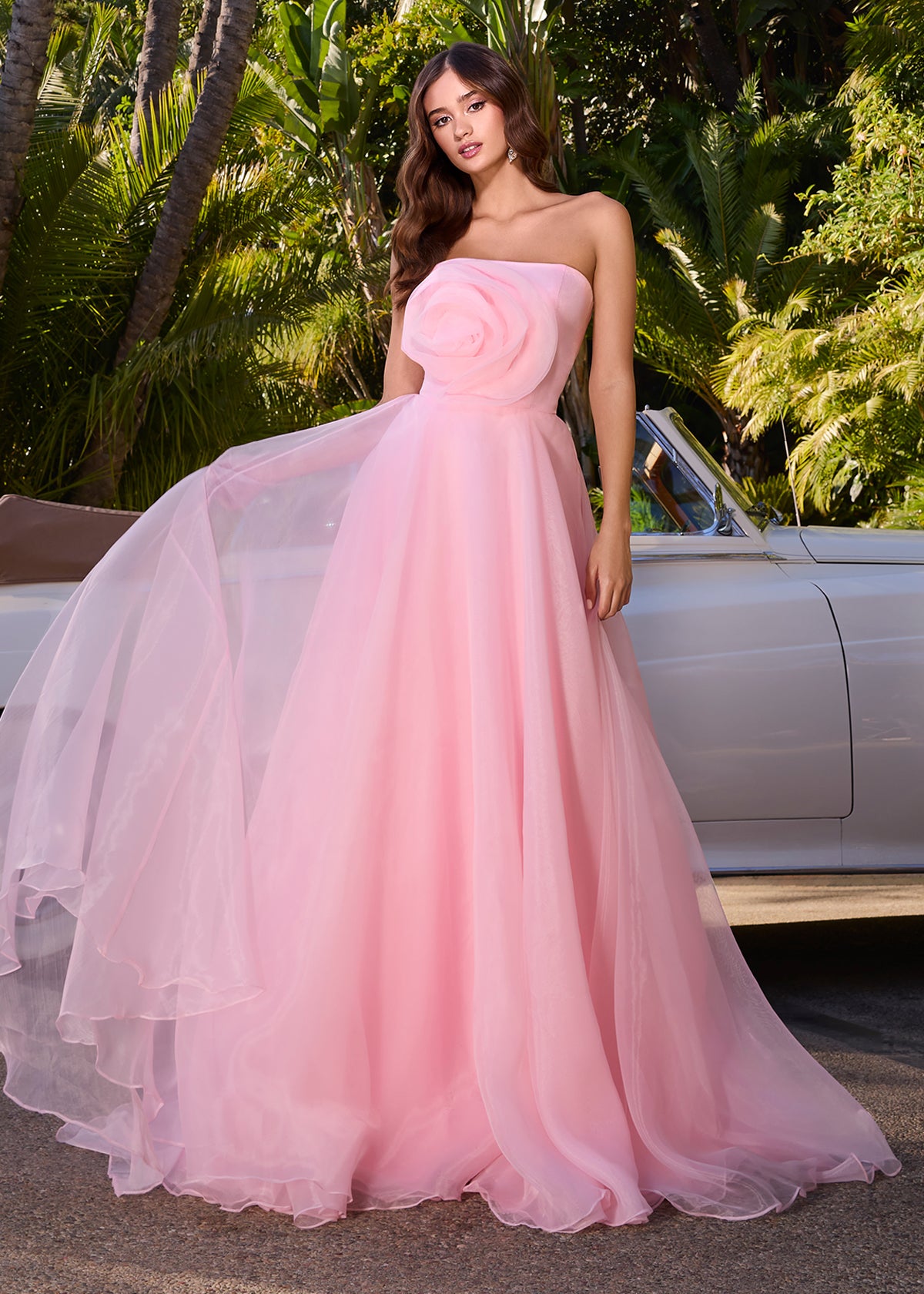 Strapless light pink gown with a large rose detail on the bodice and a flowing A-line silhouette.