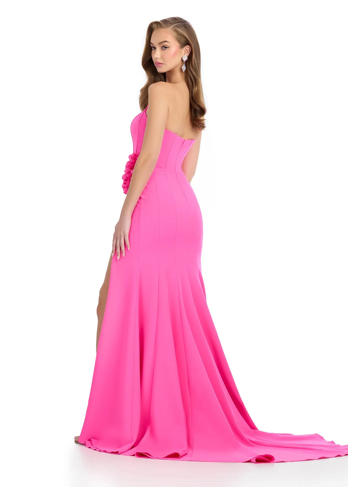 Back View - Hot pink gown with a strapless corset-style bodice, floral accents at the waist, high slit, and floor-length fitted silhouette.