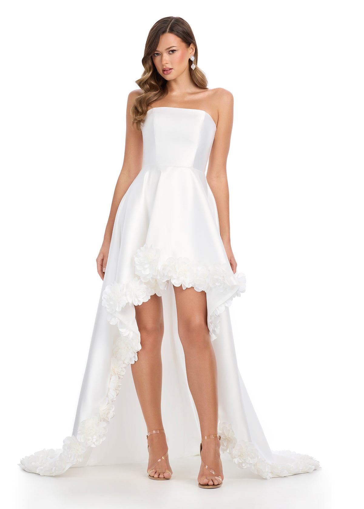 Ivory high-low gown with a strapless bodice, satin finish, and dramatic floral appliqué detailing along the hem, creating a bold and romantic statement.