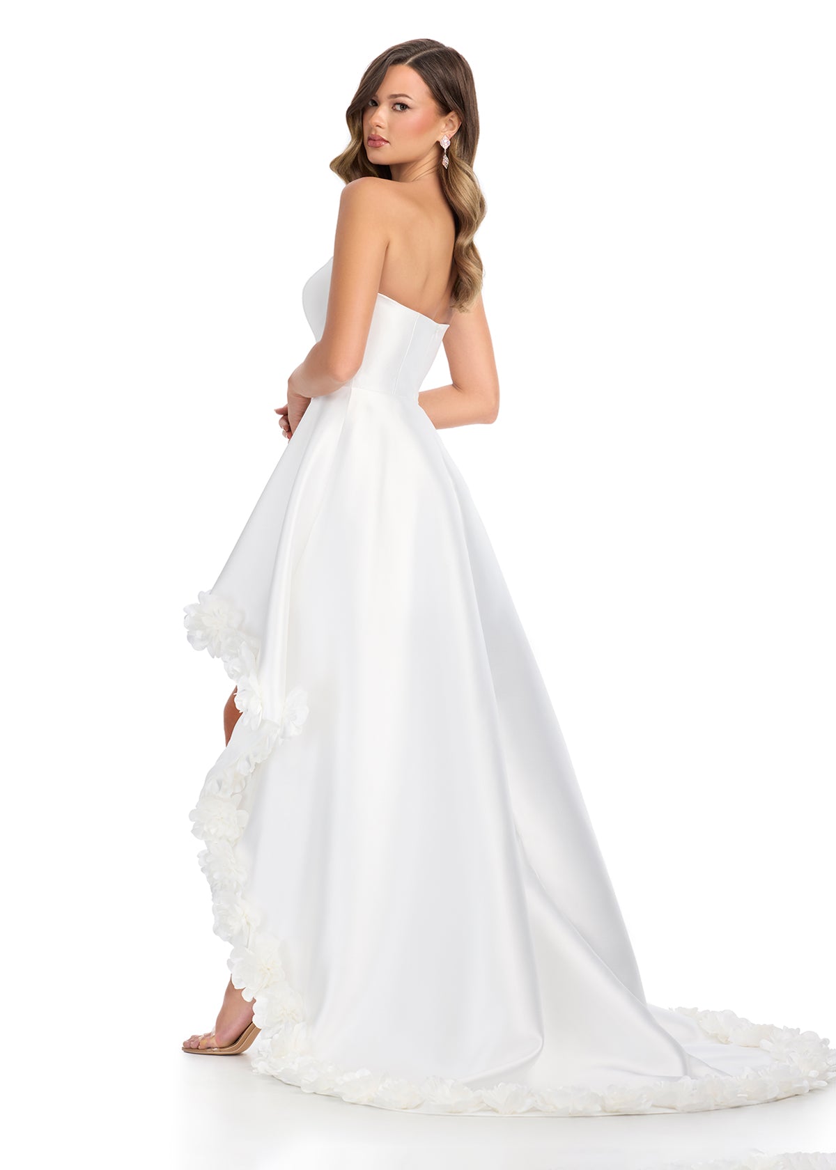 Back view - Ivory high-low gown with a strapless bodice, satin finish, and dramatic floral appliqué detailing along the hem, creating a bold and romantic statement.