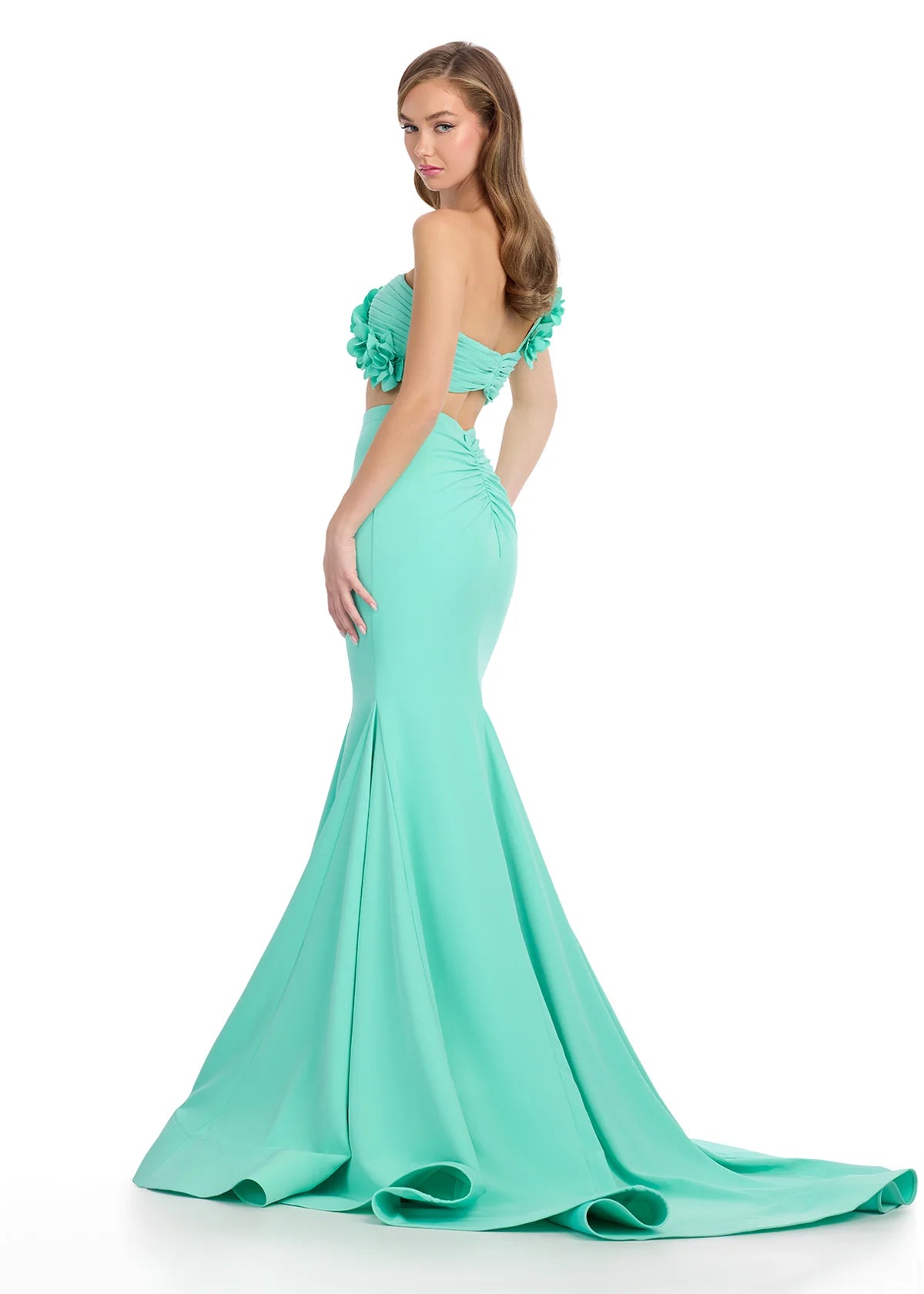 Back view of mint green two-piece gown featuring a strapless floral-embellished crop top and a fitted mermaid skirt with a dramatic flared hemline.