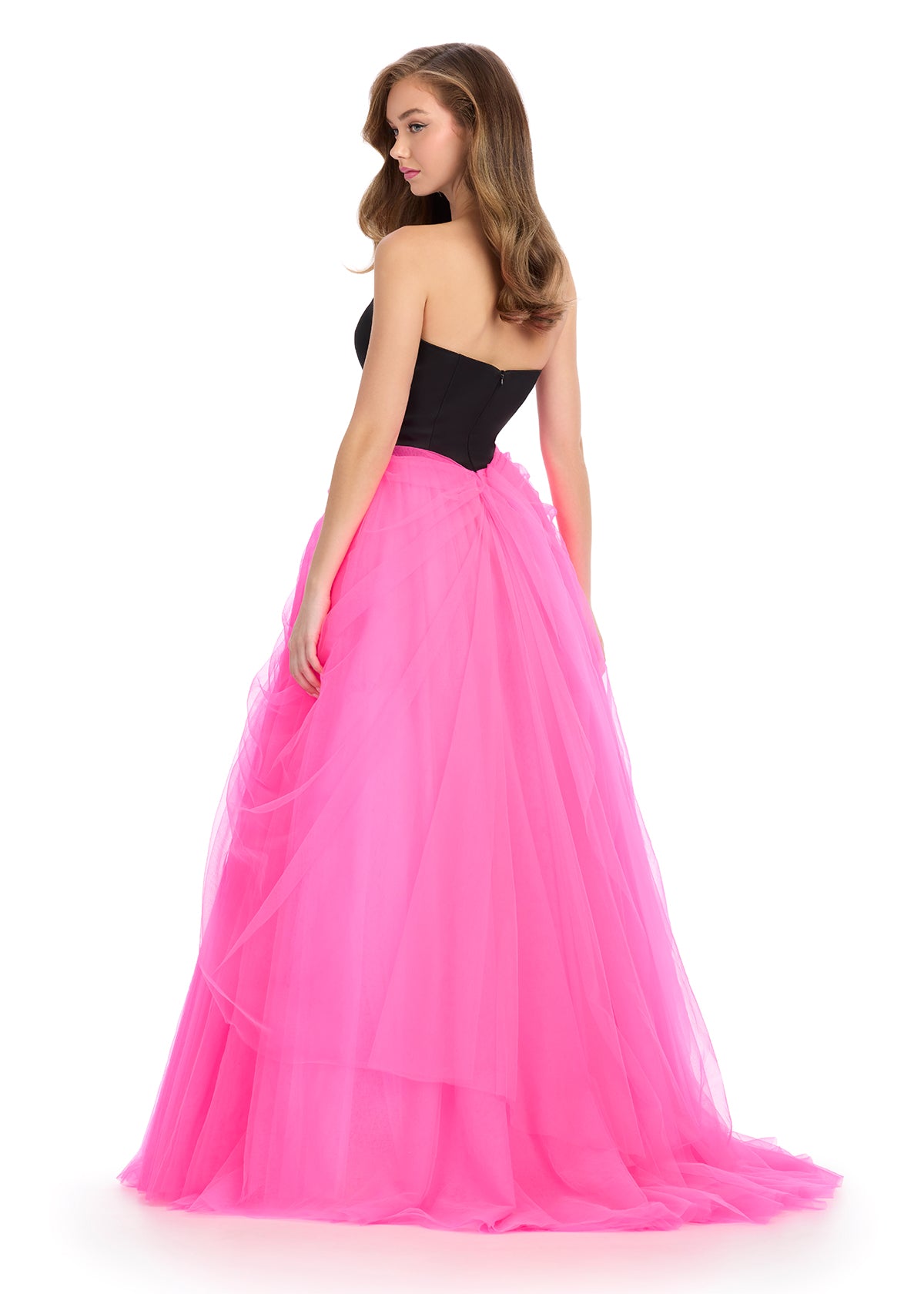Strapless gown with a fitted black bodice and a voluminous hot pink tulle skirt tied with a flowing bow detail.