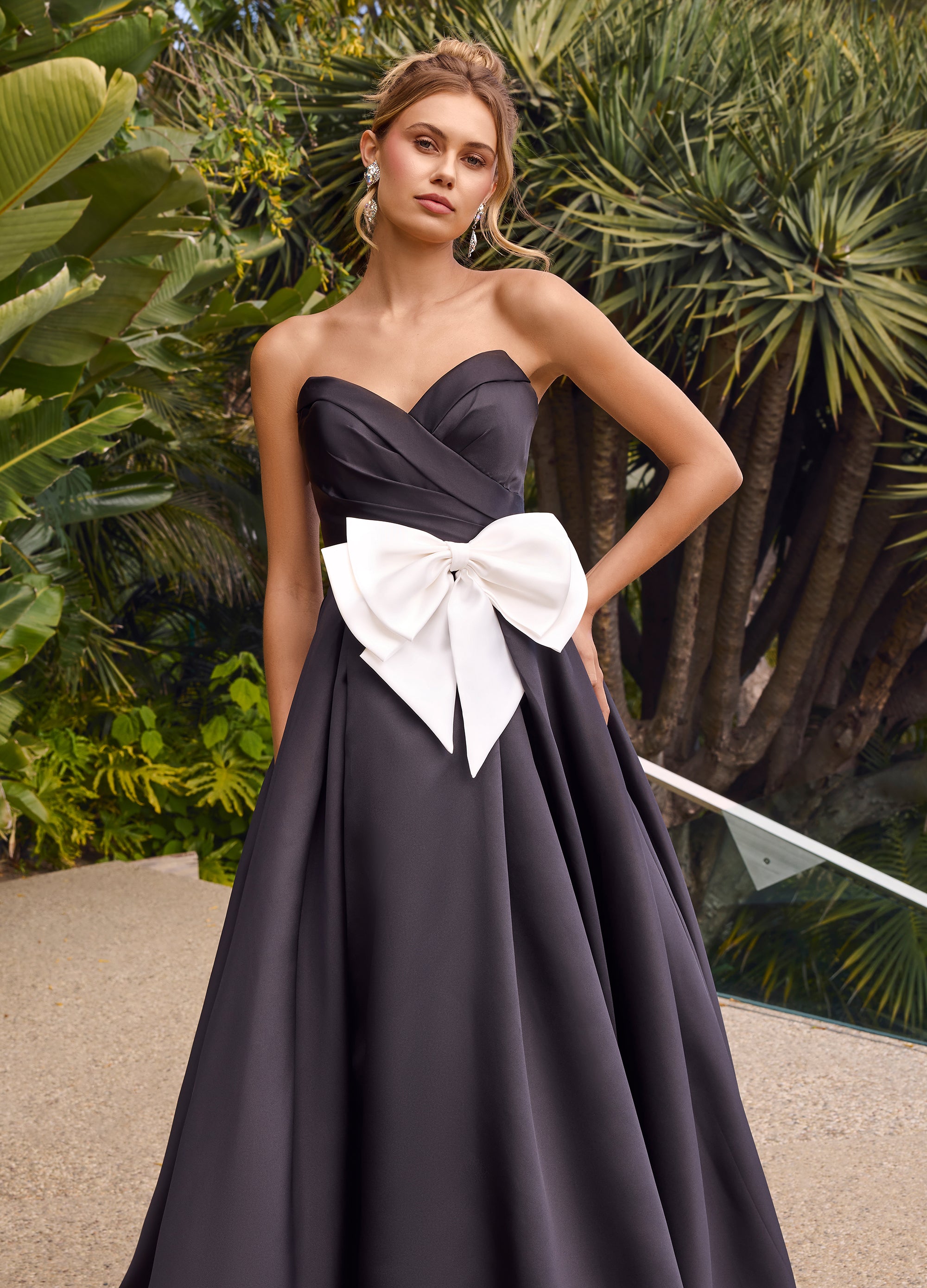 Video - ASHLEYlauren_11770 Strapless black ball gown featuring a pleated bodice, a statement oversized bow at the waist, and a dramatic full skirt with a floor-length design.