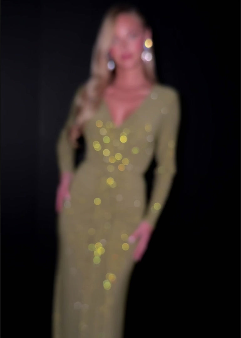 Close up video - Olive long-sleeve evening gown featuring a plunging V-neckline, ruched detailing at the waist, and a floor-length silhouette with subtle shimmering accents for timeless elegance.